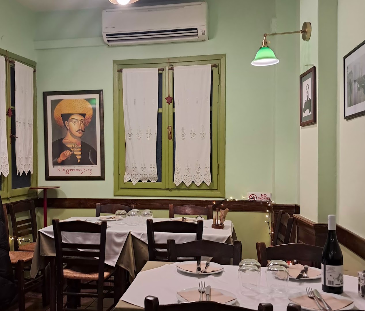 Στρωμένα τραπέζια με αναποδογυρισμένα ποτήρια έτοιμα για το σερβίτσιο, φωτιστικό με πράσινο γυάλινο καπέλο.